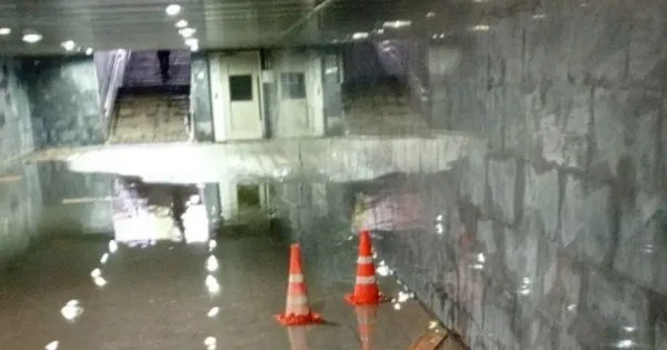 Подземный переход в Ярославле затоплен водой по щиколотку, люди идут по лужам.